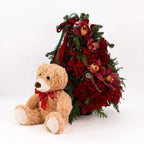 Evergreen holiday tree decorated with red roses, orchids, berries, and seasonal ribbon accents