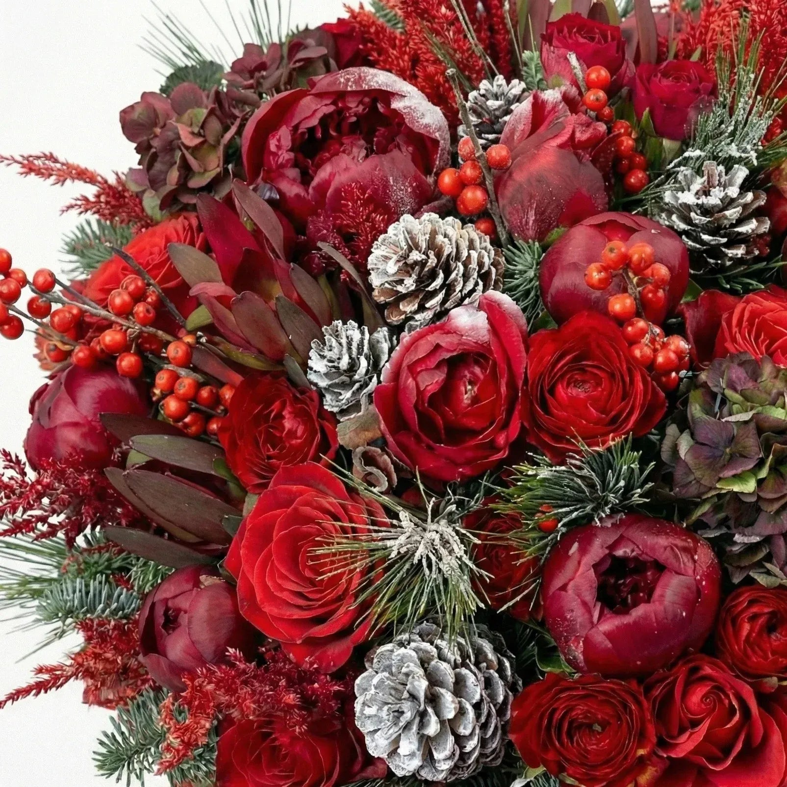 Close-up of red roses, winter foliage, and seasonal accents in Imperial Crimson Bloom flower box