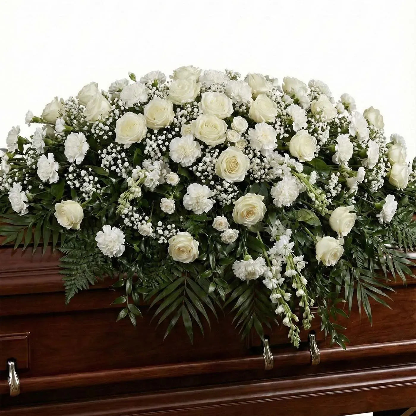 Full white casket arrangement with ivory roses, white carnations, and baby’s breath