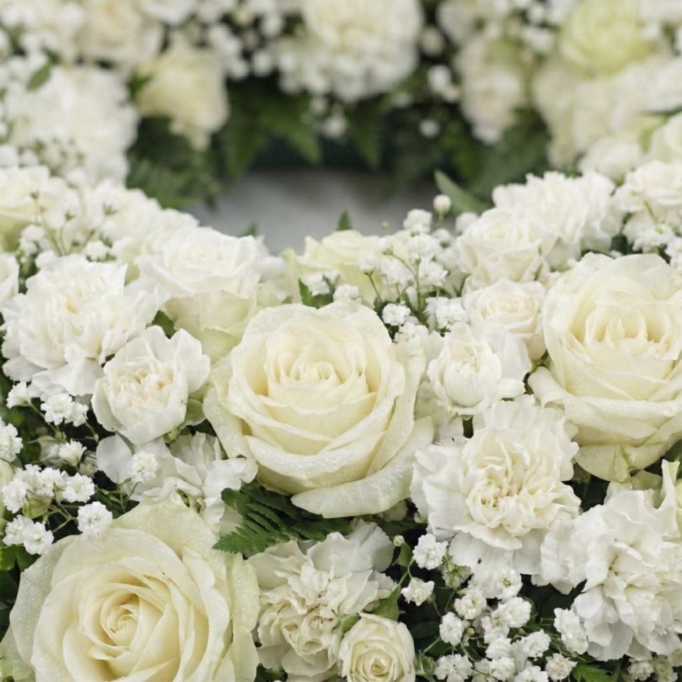 Close-up of Ivory Passage funeral wreath with ivory roses, white carnations, baby’s breath, and fern greenery