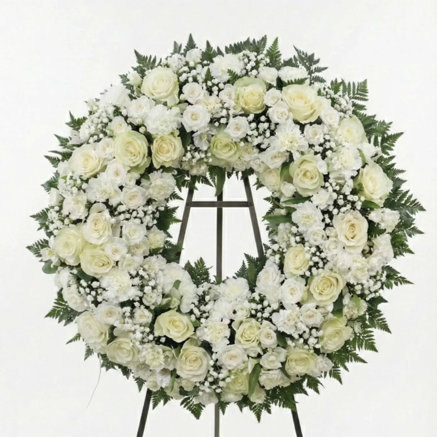 A full circular wreath symbolizing remembrance and continuity. Ivory roses and white blooms are arranged densely with soft greenery, creating a classic and respectful tribute suitable for services or graveside ceremonies.