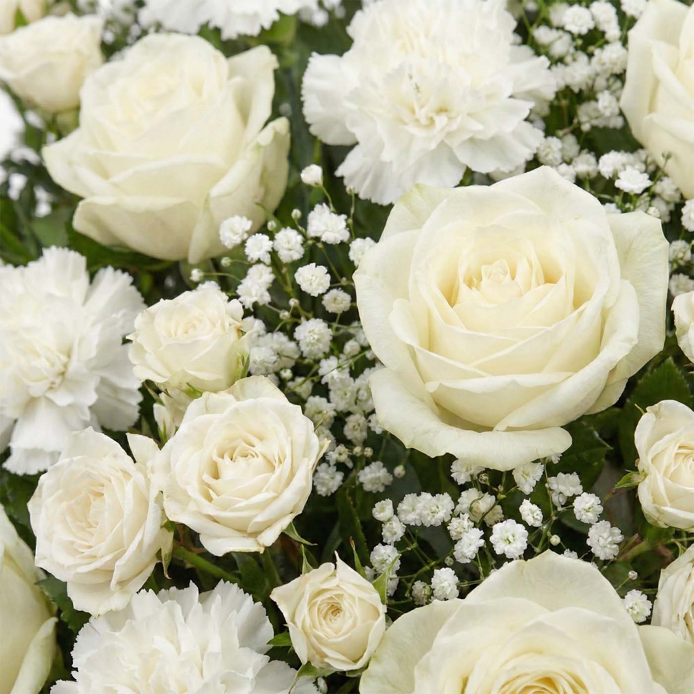 Close-up of Ivory Passage sympathy basket with ivory roses, white carnations, baby’s breath, and greenery