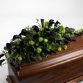 Modern casket arrangement with dark purple calla lilies and greenery