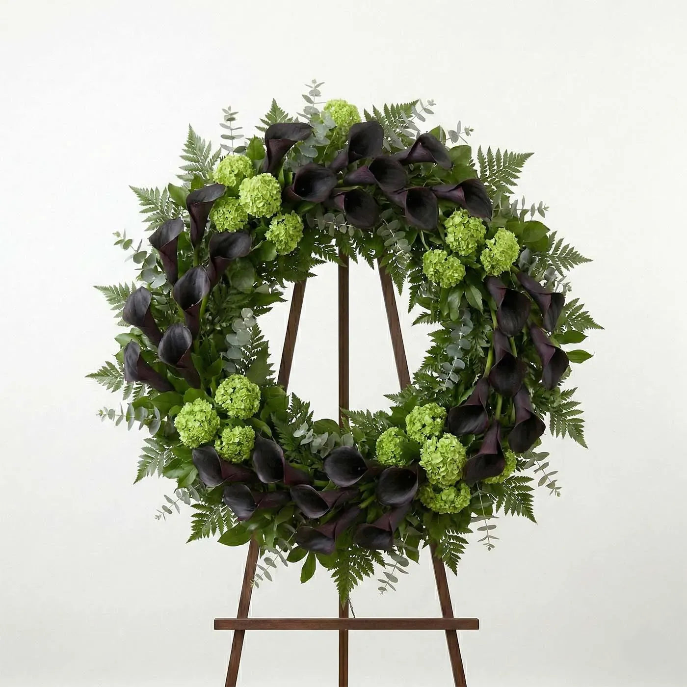 Modern funeral wreath with dark purple calla lilies and green hydrangea