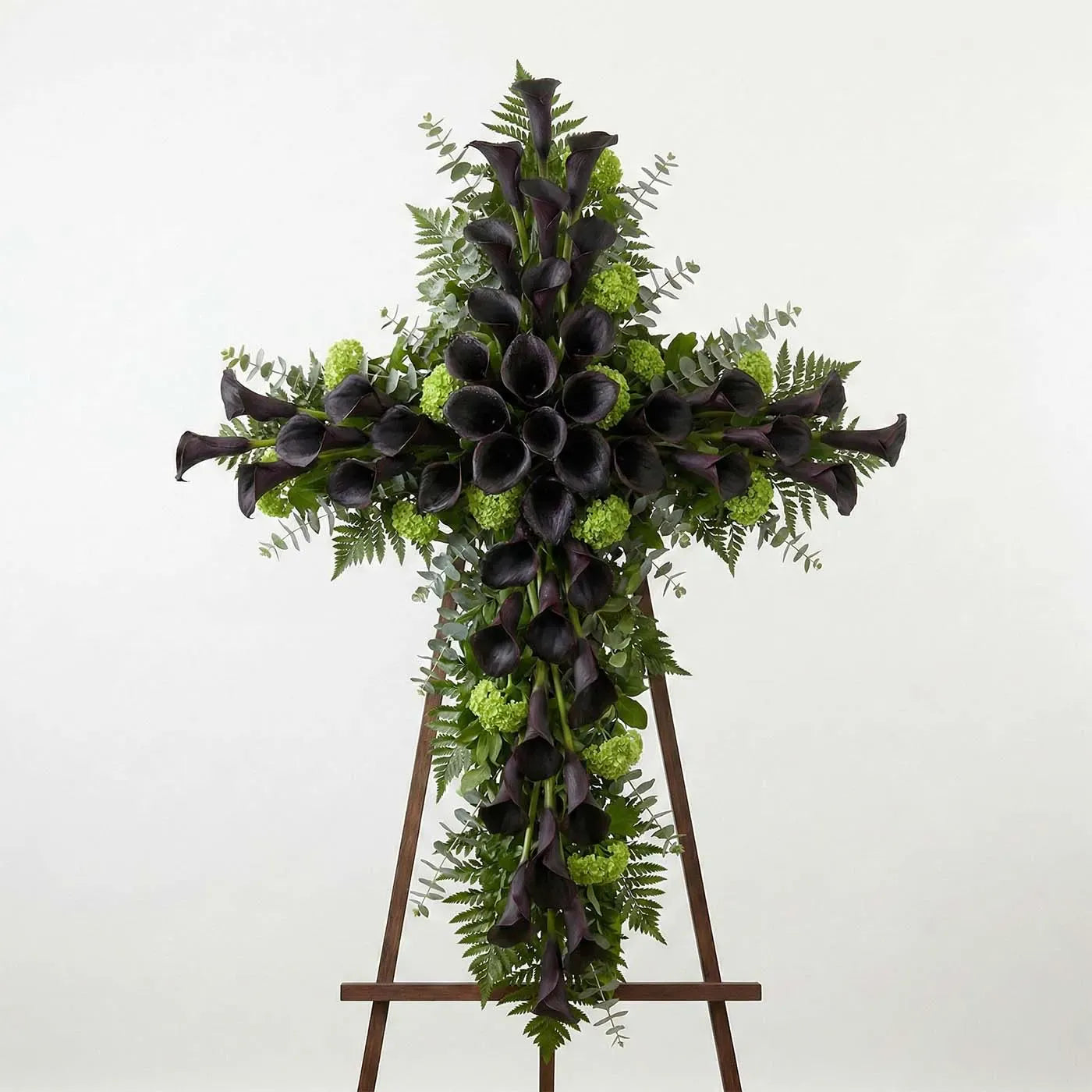 Modern standing cross with dark purple calla lilies and greenery