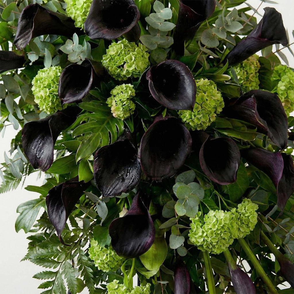 Close-up of calla lilies and greenery in standing funeral spray