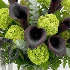 Close-up of dark purple calla lilies and hydrangea in a modern sympathy vase