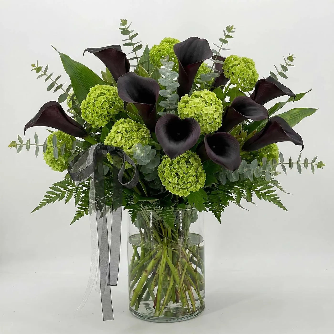Modern sympathy vase with dark purple calla lilies and green hydrangea
