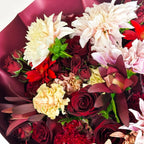 Close-up view of Midnight Ruby bouquet with red roses, dahlias, gerbera daisies, and blush chrysanthemums