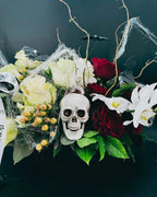 Close-up of Midnight Spell Arrangement with skull, cobwebs, ivory roses, and orchids