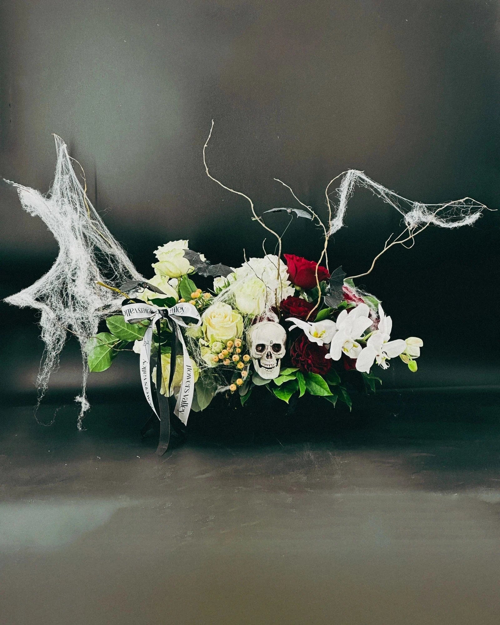 Full view of Midnight Spell Arrangement with eerie cobwebs, roses, orchids, and skull
