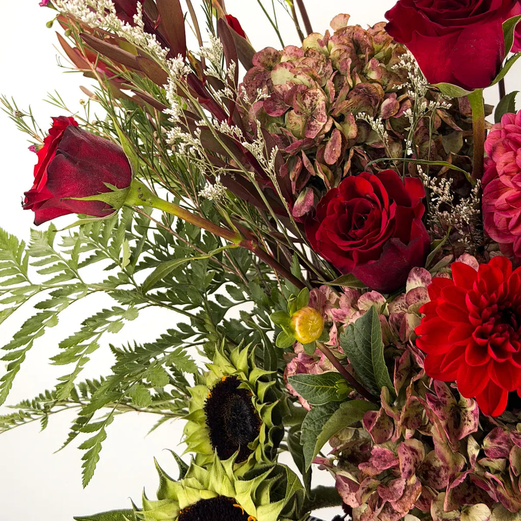 Close-up of red roses, pink dahlias, burgundy leucadendron, antique hydrangea and sunflowers in the Mulberry Hearth arrangement by Flowers Valley