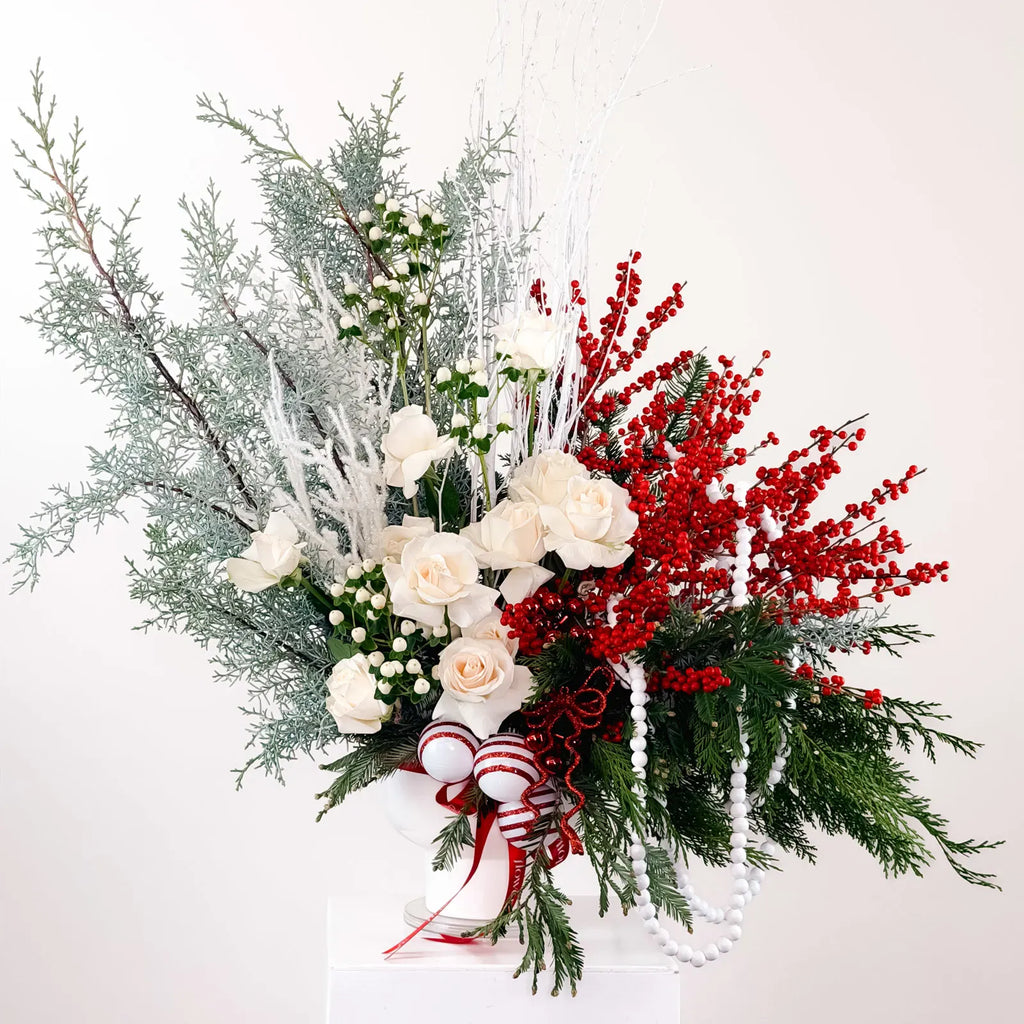 Nordic Holiday Bloom arrangement with ivory roses, red berries, and winter greenery
