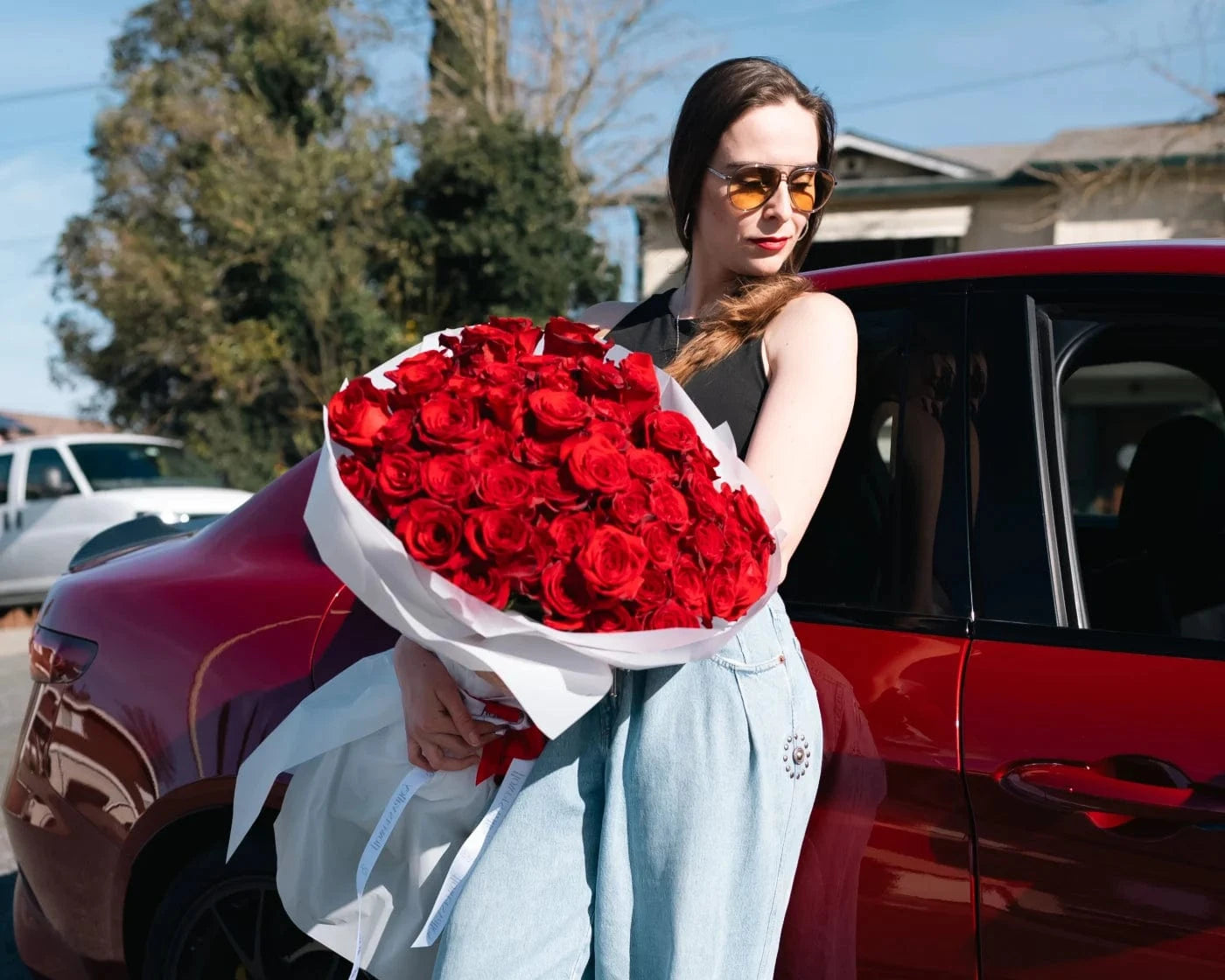 Woman holding a luxury bouquet of red roses beside a car in Novato – Flowers Valley delivery