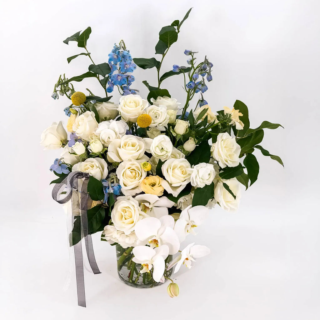 Elegant white sympathy flowers with orchids and greenery designed by Flowers Valley