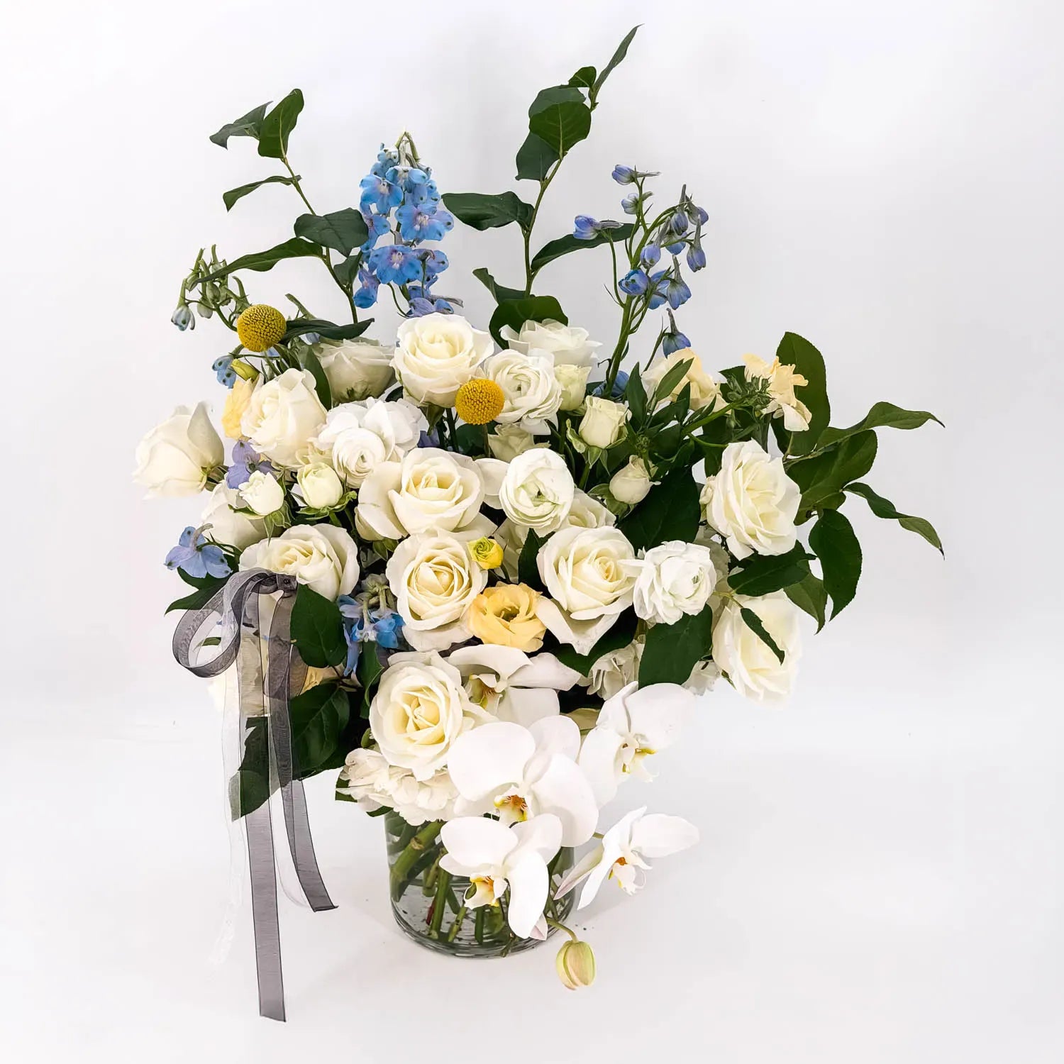 Elegant white sympathy flowers with orchids and greenery designed by Flowers Valley