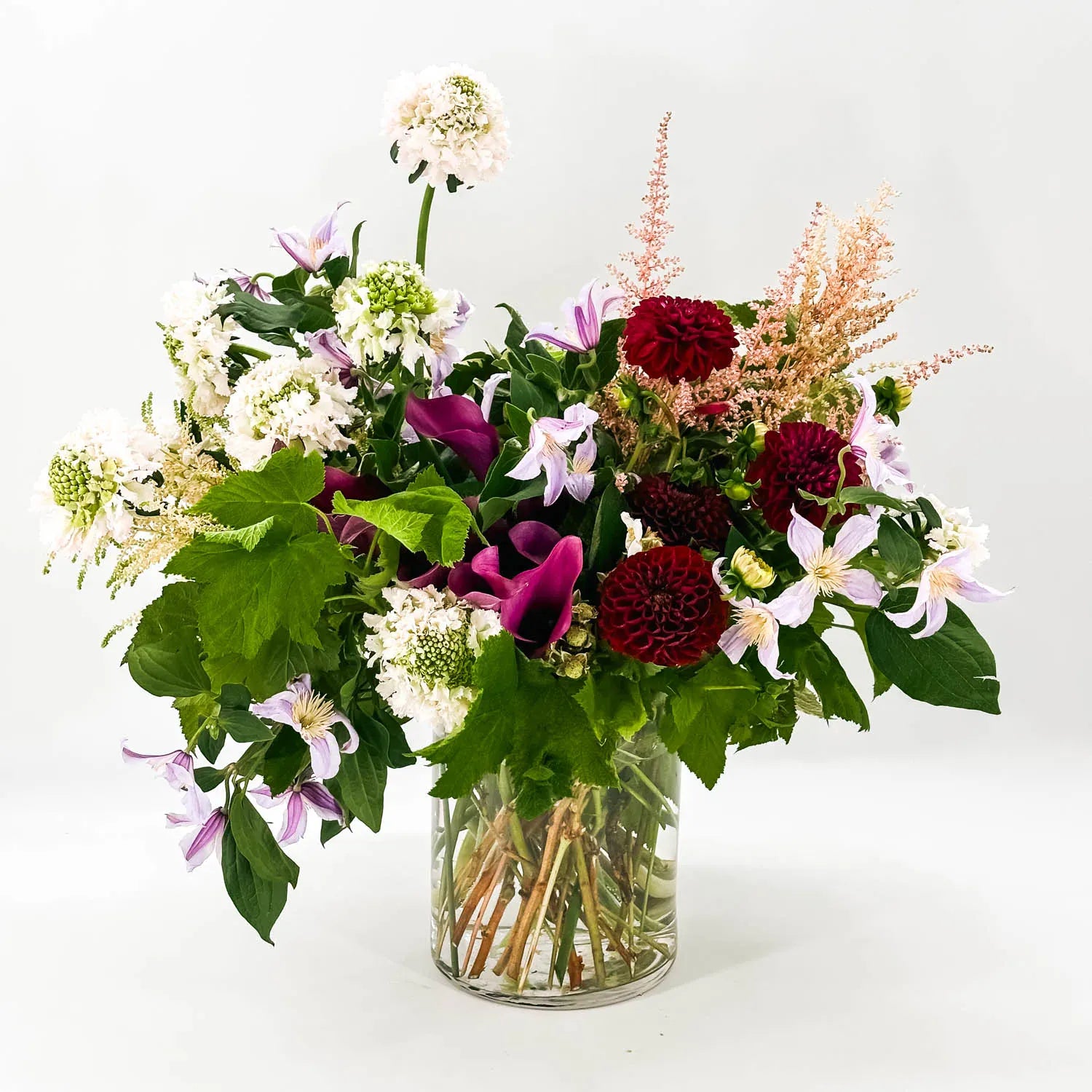 Sympathy flower arrangement with burgundy dahlias, lavender blooms, and natural greenery