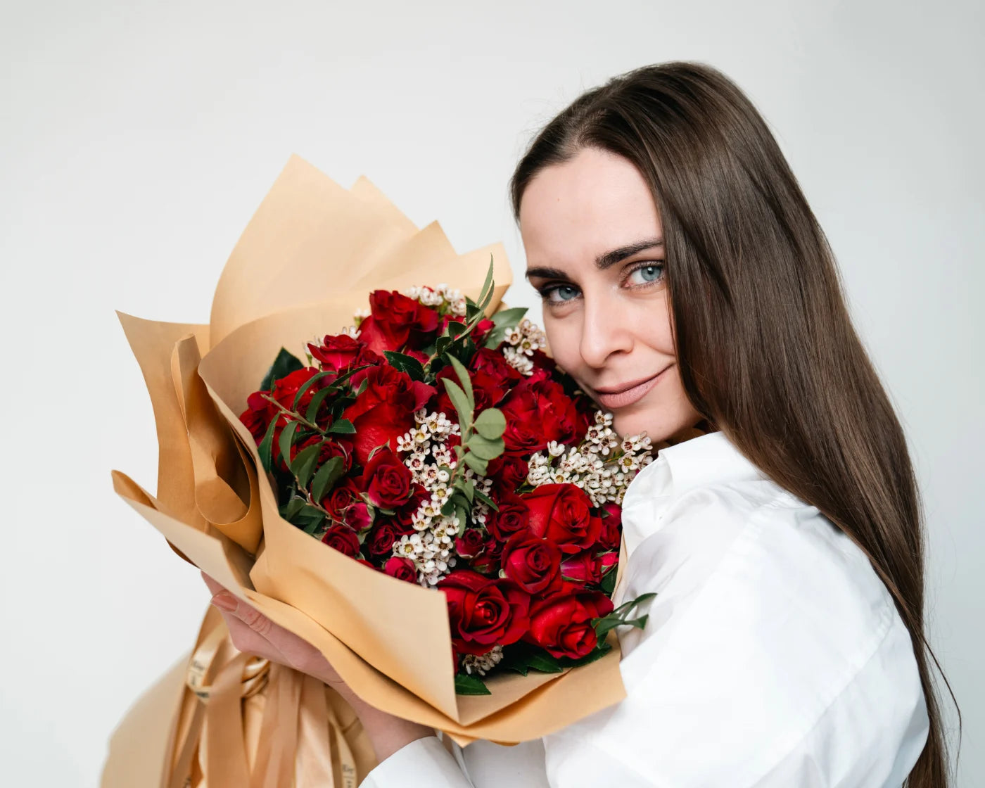 Woman holding a bouquet of red roses with white accent flowers wrapped in craft paper – Flowers Valley flower delivery in Half Moon Bay, CA