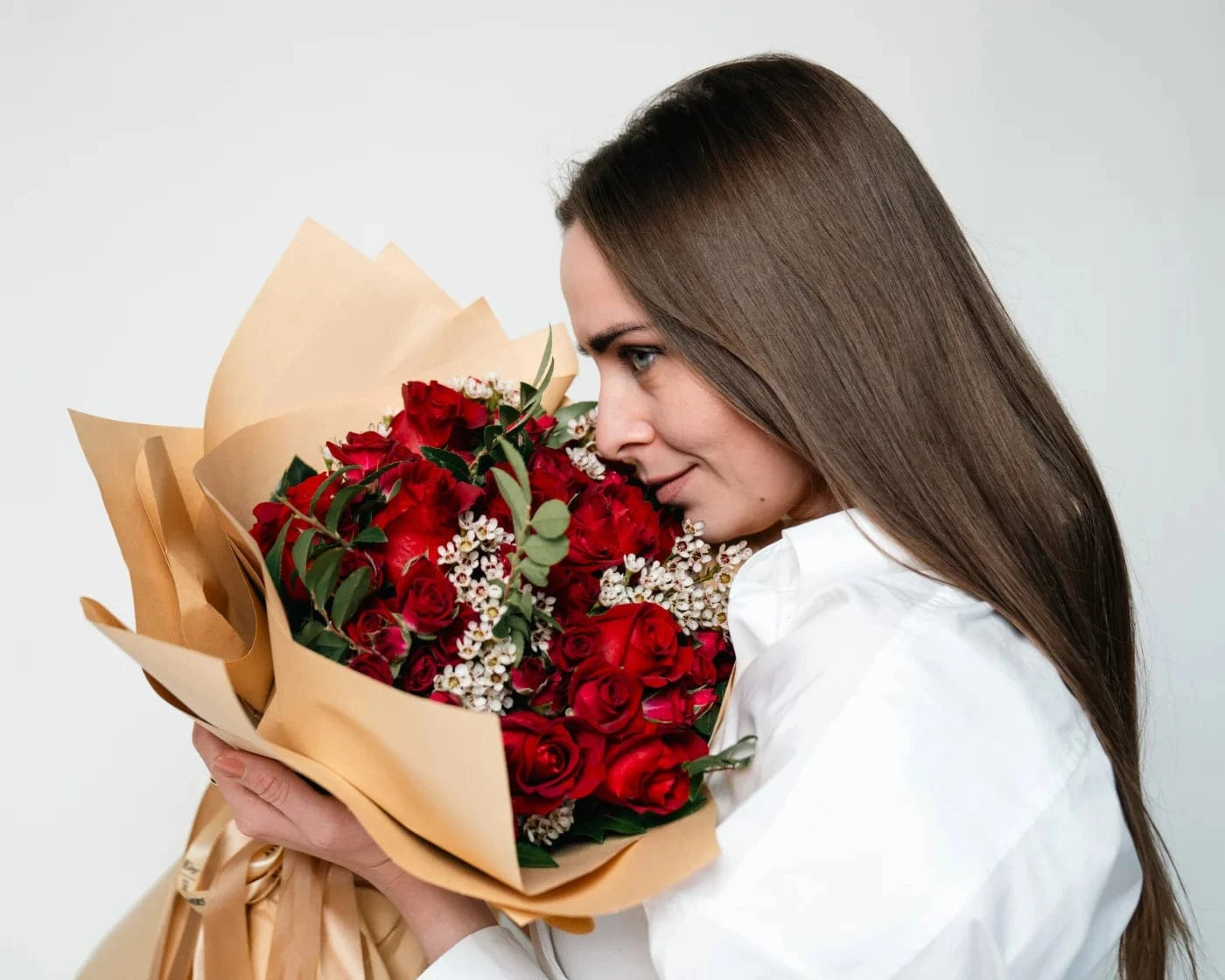Woman holding a bouquet of red roses with white accent flowers wrapped in craft paper – Flowers Valley flower delivery in Hillsborough, CA