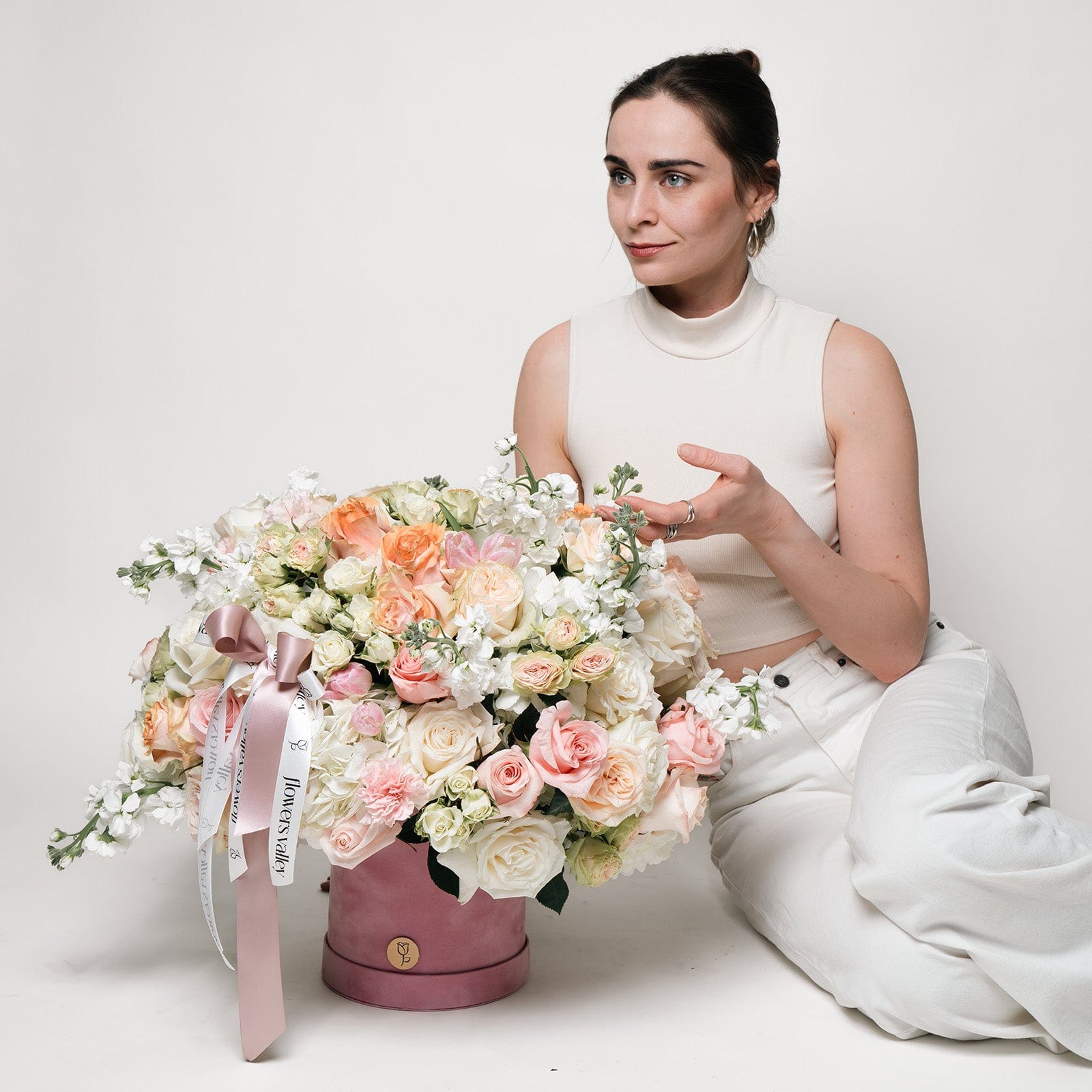 Elegant woman admiring a large, luxurious hatbox flower arrangement featuring pink, peach, and white roses, ideal for special occasion flower delivery from Flowers Valley in Walnut Creek, CA.