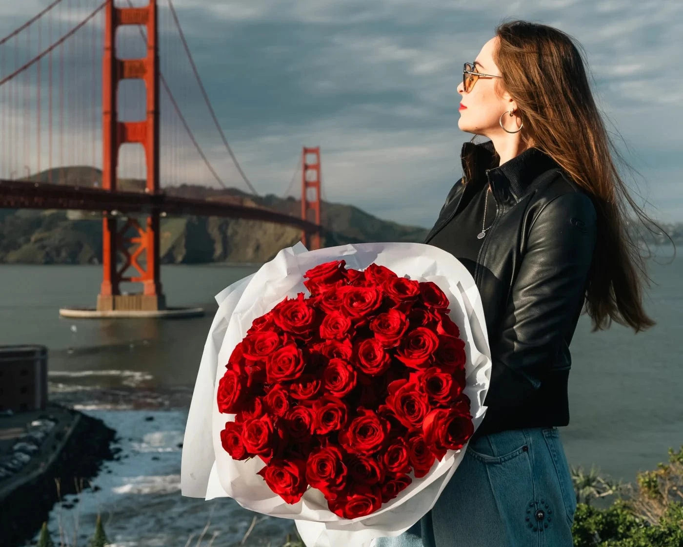 Woman holding a large bouquet of red roses near Golden Gate Bridge in San Francisco – luxury flower delivery by Flowers Valley