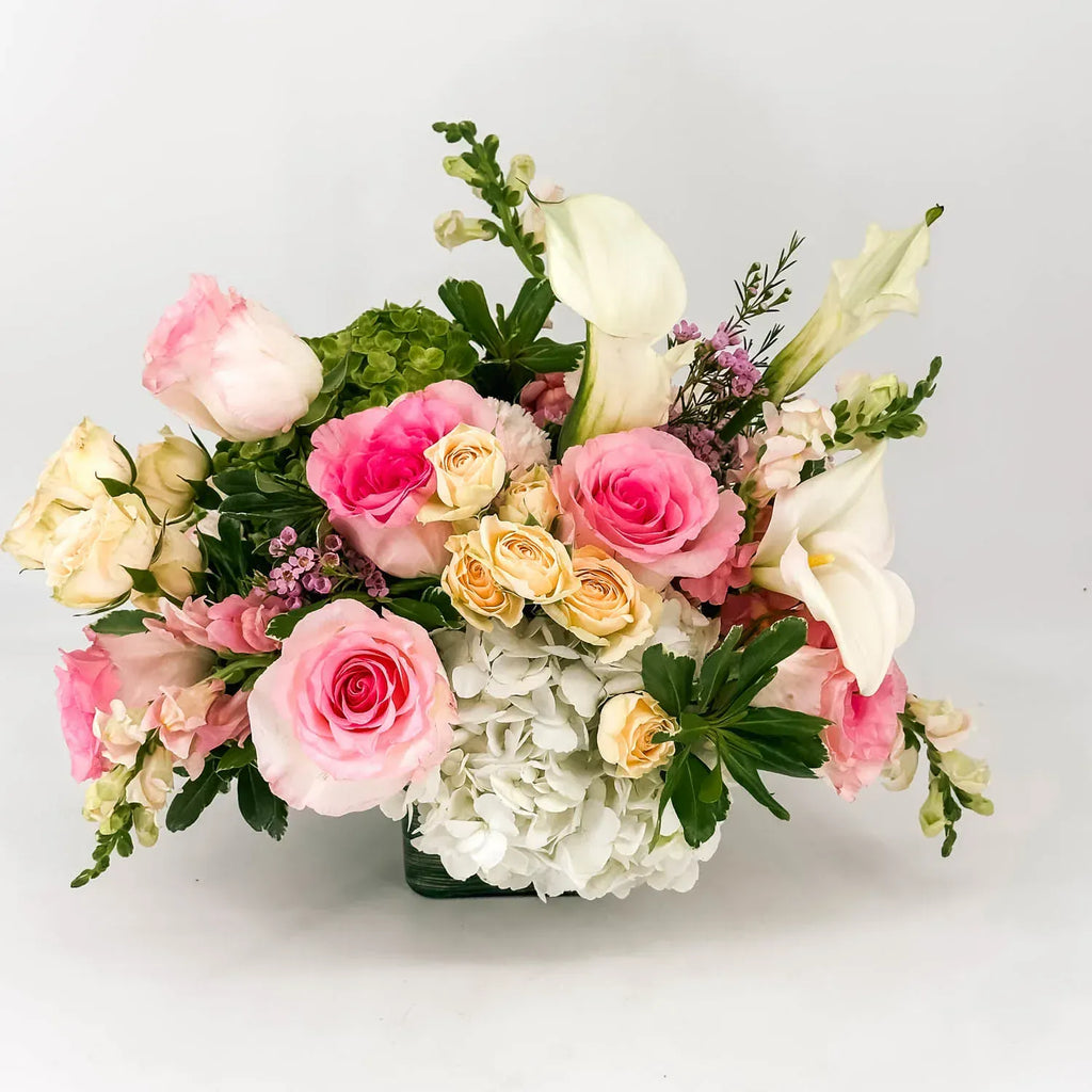 Close-up of pink roses, calla lilies, and white hydrangea in a sympathy arrangement
