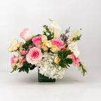 Sympathy flower arrangement with pink roses, white hydrangea, and calla lilies in a glass vase