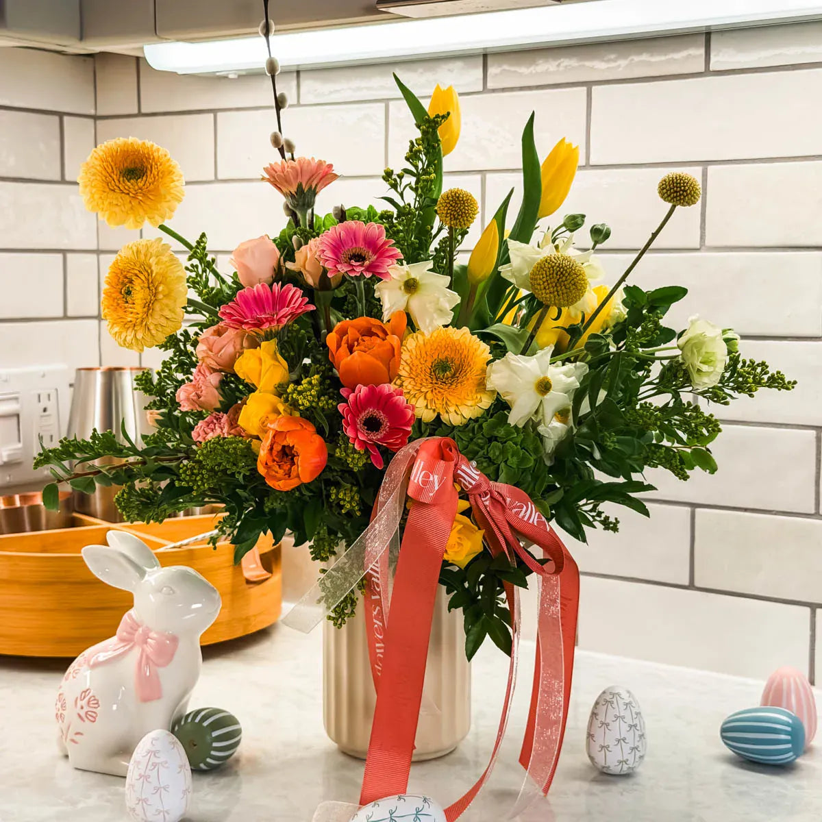 Spring Easter flower arrangement on kitchen counter with Easter decorations and pink ribbon