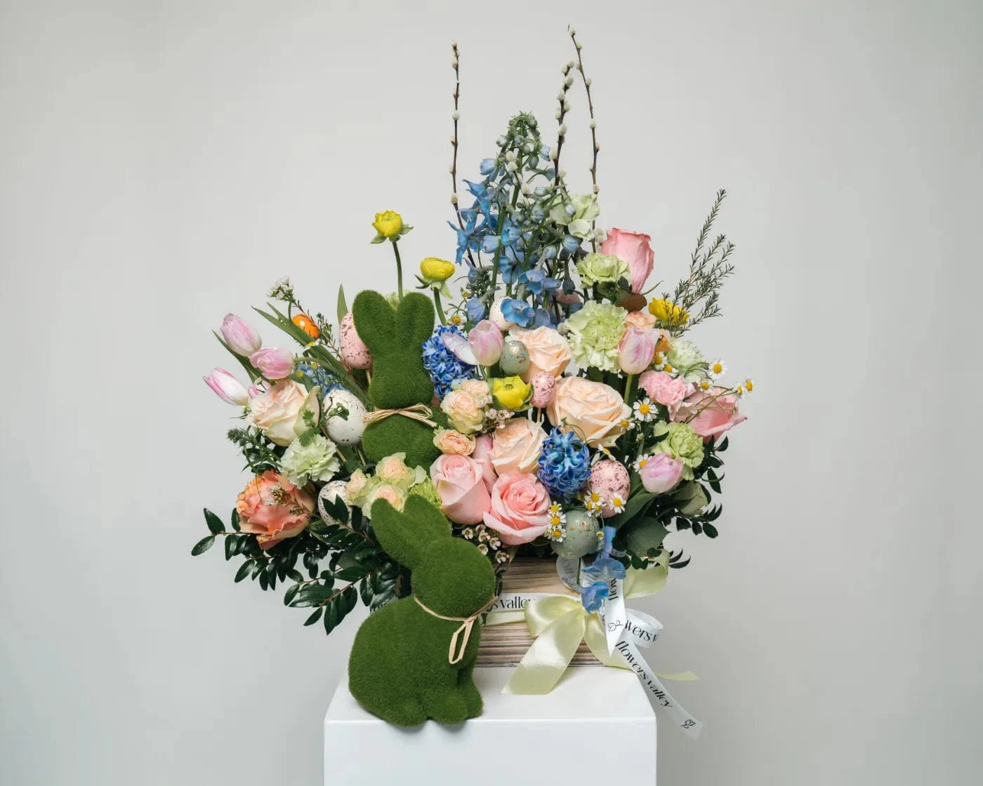 Charming spring basket with pastel roses, hydrangeas, and seasonal blooms, decorated with a green bunny figure – Flowers Valley Windsor flower delivery