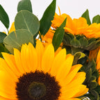 Close-up view of vibrant sunflowers with green eucalyptus, part of the Summer Glow flower arrangement, for premium Bay Area delivery from The Flowers Valley.