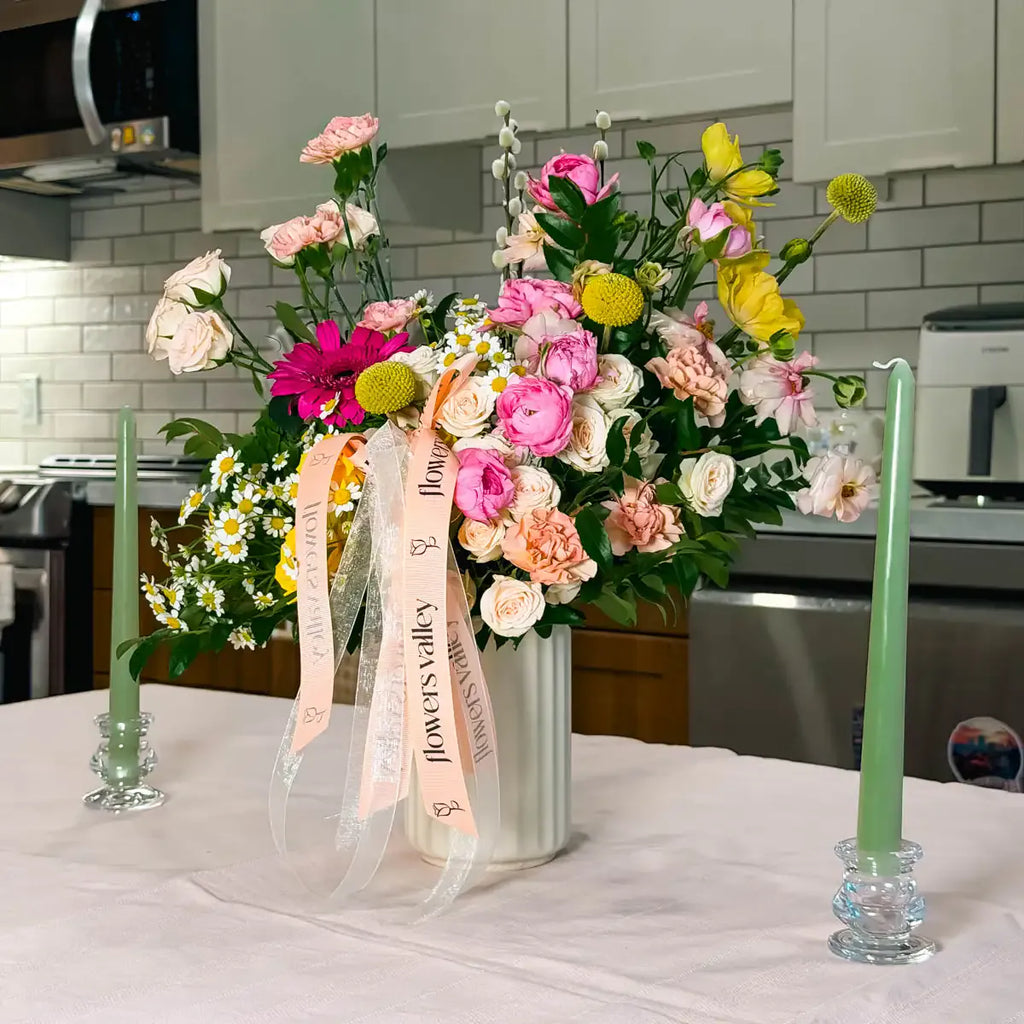 Sunlit Garden vase arrangement with pink ranunculus, yellow craspedia, and chamomile in a fluted ceramic vase — Flowers Valley Bay Area florist