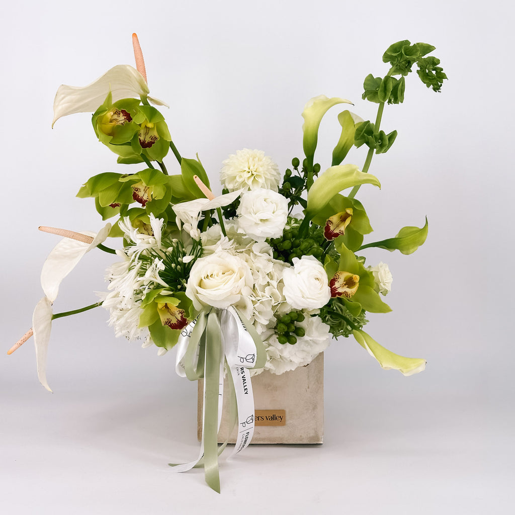 Modern white and green flower arrangement, the Urban Serenity Arrangement, in a concrete vase, available for local delivery from Flowers Valley