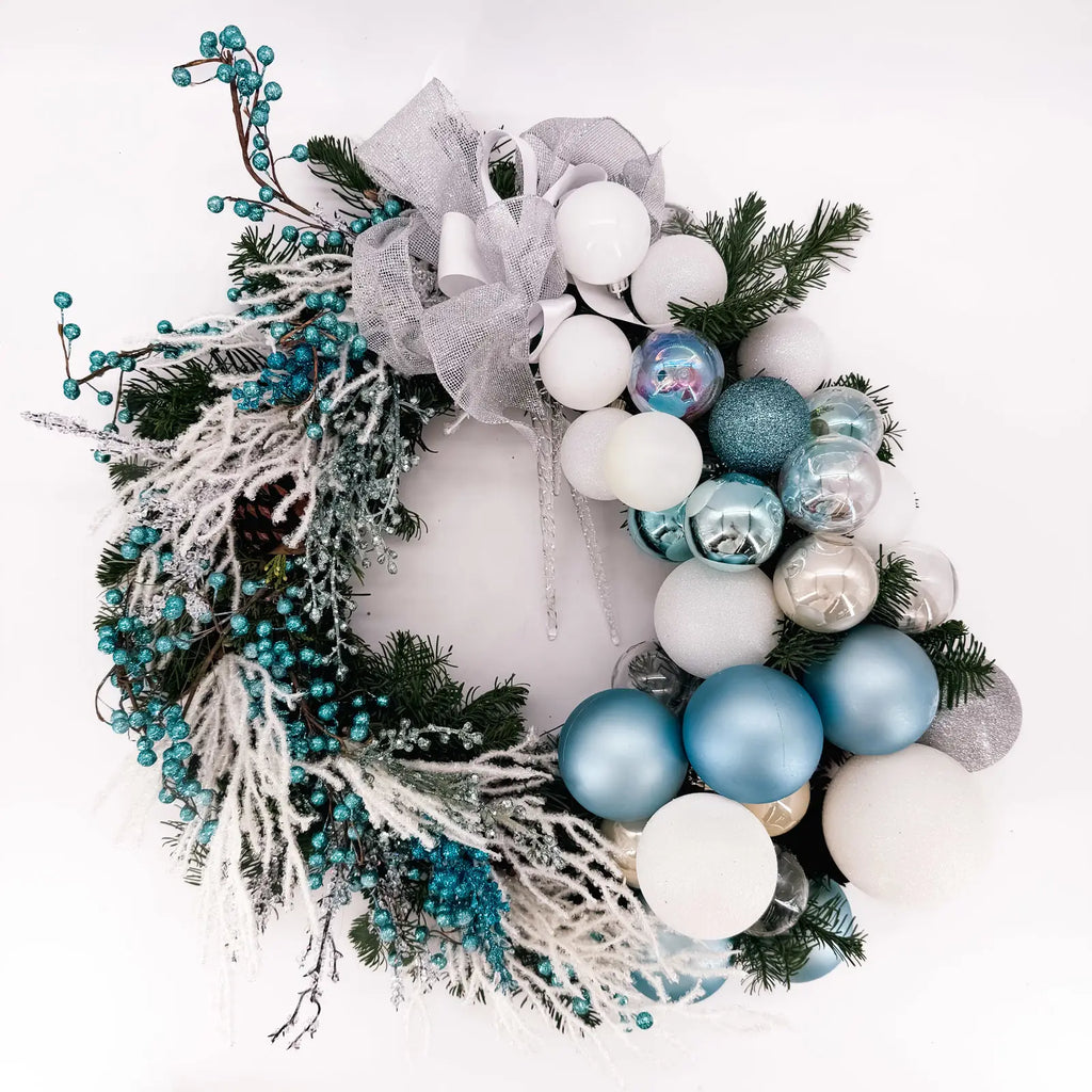 Luxury winter wreath with frosted branches, blue ornaments, and silver bow by Flowers Valley.