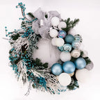 Luxury winter wreath with frosted branches, blue ornaments, and silver bow by Flowers Valley.