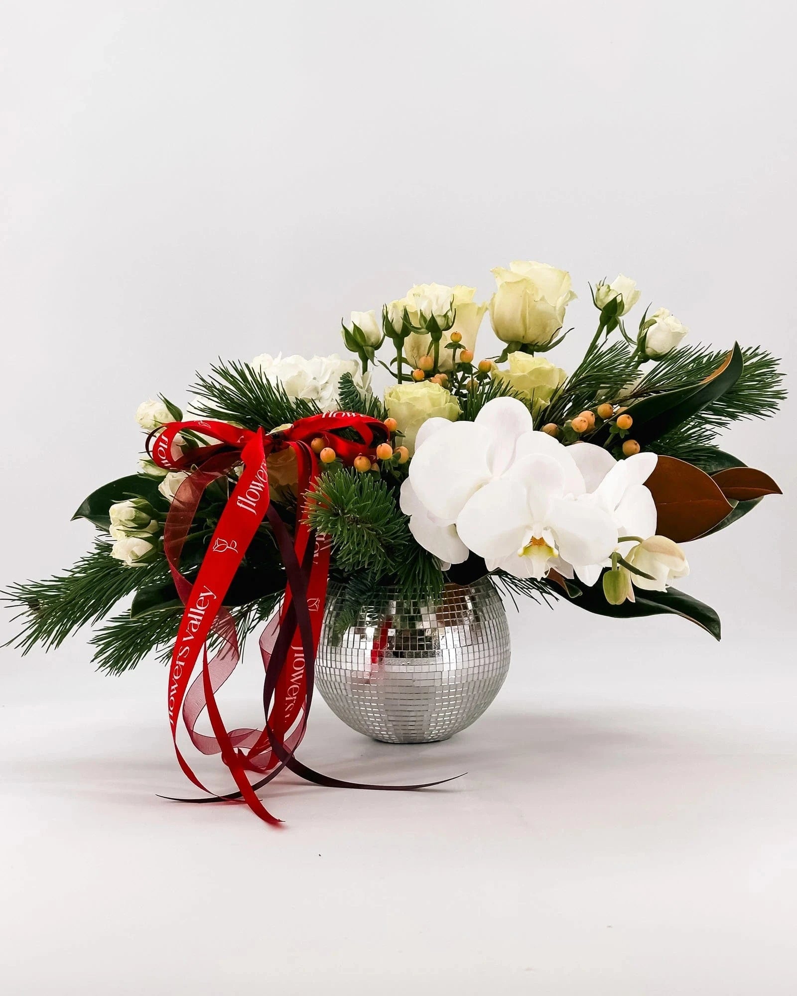 Side view of Winter Grace Arrangement featuring orchids, roses, hydrangeas, and red ribbons