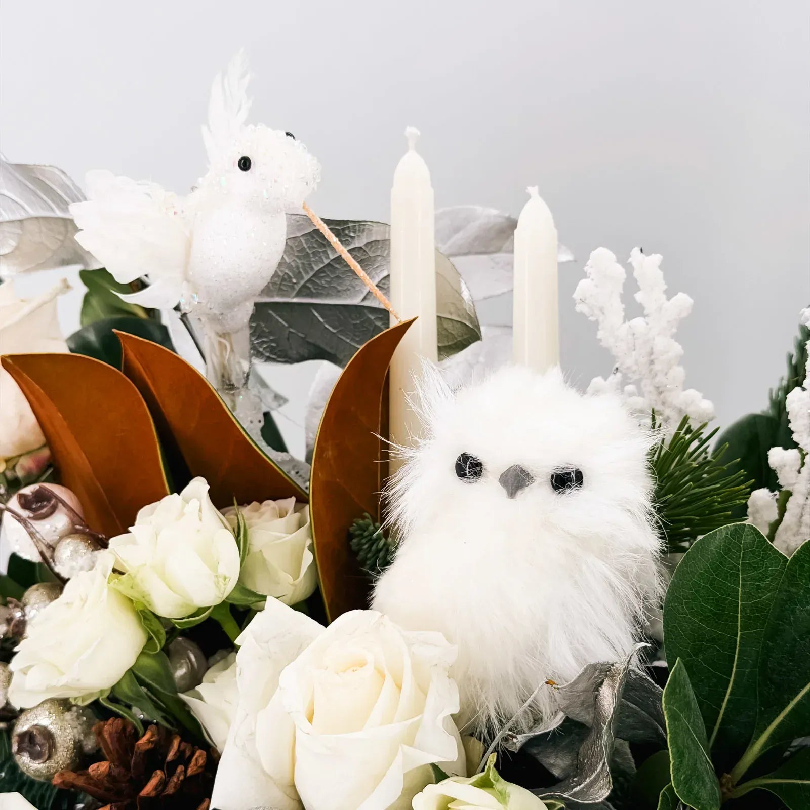 Close-up of white owl and snowbird in luxury holiday flower arrangement
