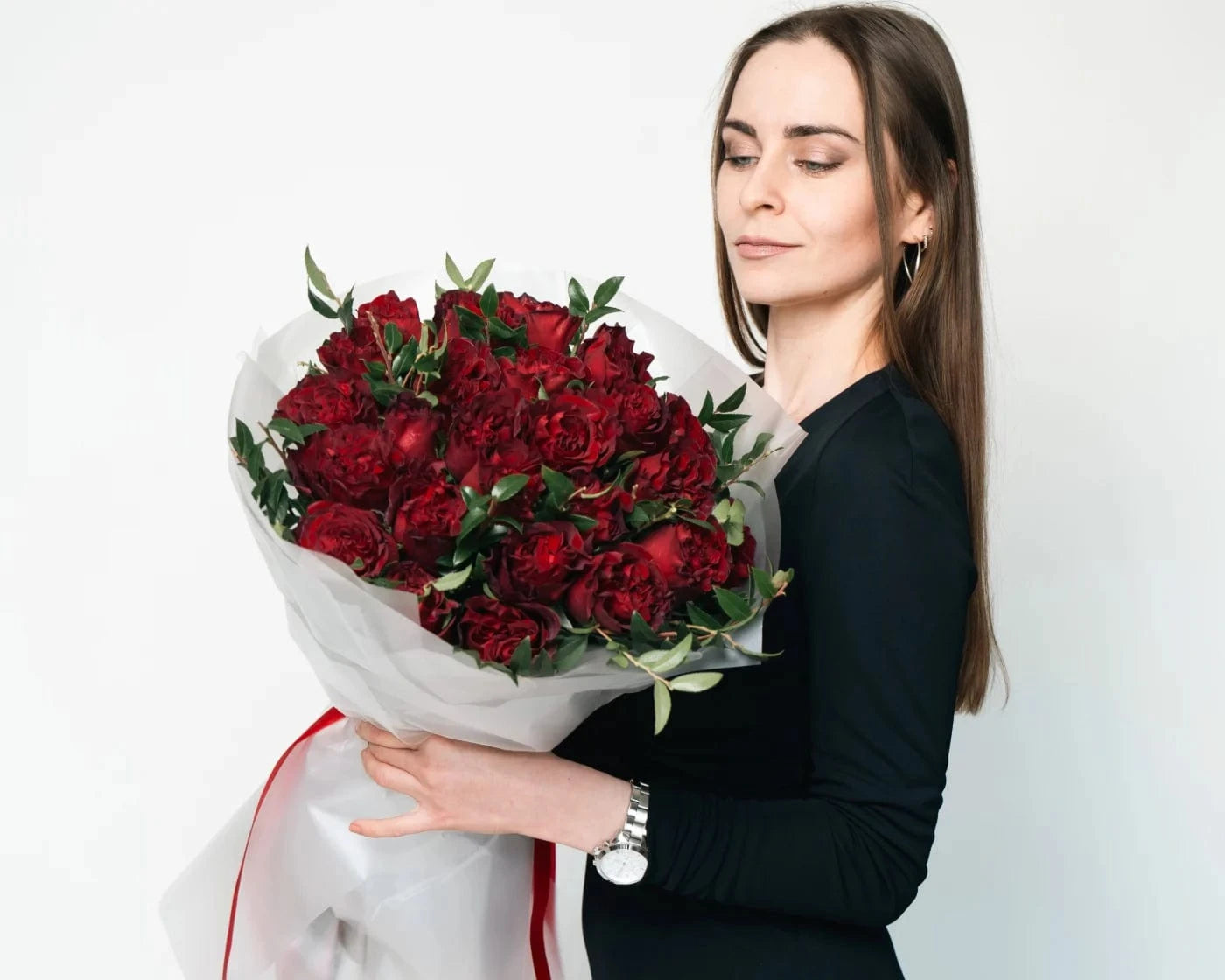 Woman holding a bouquet of deep red carnations with greenery, wrapped in white paper – Flowers Valley Gilroy flower delivery