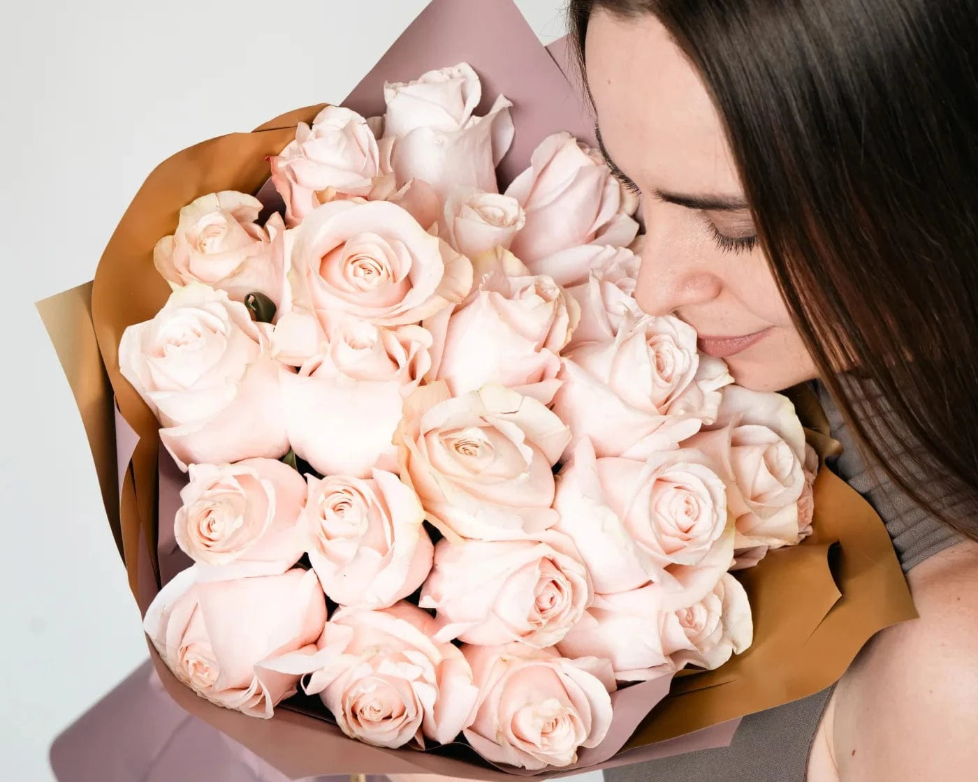 Woman smelling a bouquet of elegant white roses wrapped in pastel paper – Flowers Valley Sonoma flower delivery